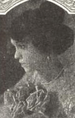 A woman in profile, her dark hair in a bouffant updo with a top bun.