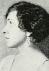 White woman with short wavy hair, in profile.