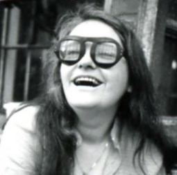 Millett looks up and smiles. She wears glasses.