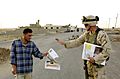 US Army soldier hands out a newspaper to a local Aug 2004