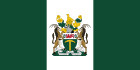 A flag with vertical green, white and green stripes, with a coat of arms on the central white stripe.
