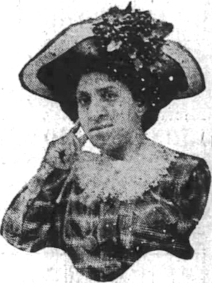 An African-American woman wearing a hat with a wide brim, and a striped dress with a lace collar