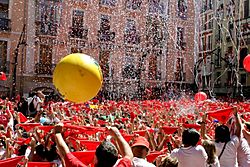 Seconds before the beginning of the San Fermín Festival in Pamplona (Spain). Town hall Square. Everybody holds his red handkerchief above his head until a firework is exploded at 12 pm; they then put it around the neck