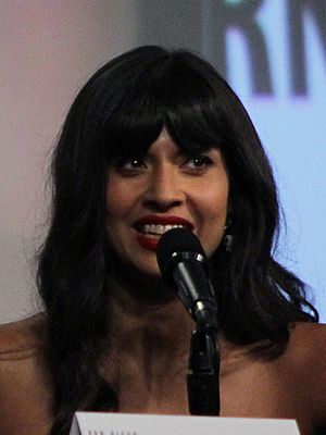 Jamil smiles with a black microphone in front of her