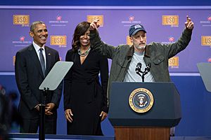 Jon Stewart tells jokes behind the president’s lectern as President Obama and the First Lady look on during the comedy show in celebration of the 75th anniversary of the USO and the 5th anniversary of Joining Forces (26240098743)