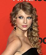 Taylor Swift wearing a black dress against a red background at the 2010 Time 100