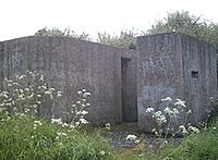 A rear view of an eastern Command Type pillbox showing the huge blast wall covering the entrance.