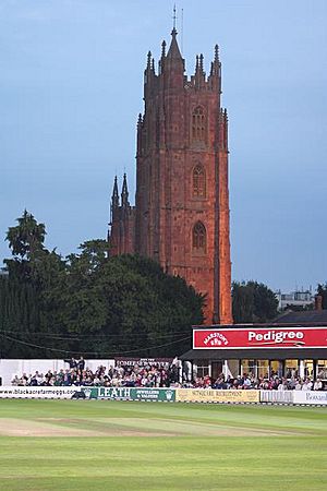 Cricket ground in front of a church tower.
