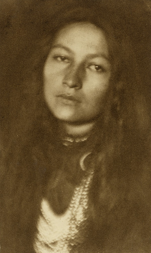 Sepia toned image of bust Native American woman looking straight into the camera.