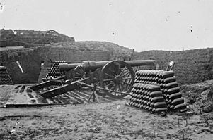 two cannon on a ground level platform with two stacks of percussion shells