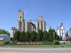 Sign welcoming visitors to Breckenridge, Michigan with large grain and corn silos rising above in the background