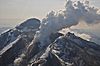 Snow-capped mountains, with a large plume of steam rising from one peak
