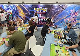 Adults (hands holding cards) competing at a Pokémon TCG junior tournament