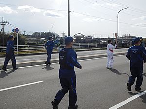 Tokyo 2020 torch relay at Mibu, Slot 9th runner with police