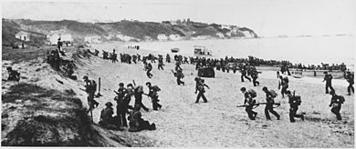 Near Algiers, "Torch" troops hit the beaches behind a large American flag "Left" hoping for the French Army not fire... - NARA - 195516