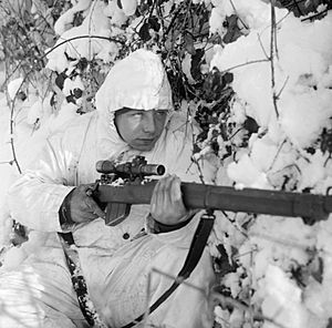 A 6th Airborne Division sniper on patrol in the Ardennes, wearing a snow camouflage suit, 14 January 1945. B13676