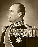 King Olav dressed in military regalia, looking to the side with a row of medals pinned to his jacket, adorned with a sash and epaulettes