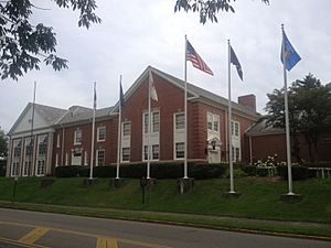 View of the front brick exterior entrance of the museum with six flag poles set slightly up a hill from the 2nd street road surface.