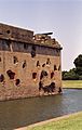 behind a water-filled moat, Fort Pulaski's brick masonry wall is pot-marked with cannonball strikes.