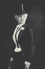 Young woman dressed as a man, in white tie, top hat and a monocle