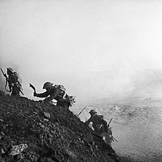 Ghurkas advance through a smokescreen up a steep slope in Tunisia, 16 March 1943. NA1096