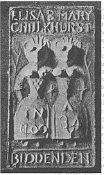 Two highly simplified female figures standing side by side, with snout-like faces, extremely narrow waists and very wide hips. The figures each only have one arm, and appear to be joined at the shoulder. Crown-like points rise from their heads. Next to each figure is a branch. The words "Eliza & Mary Chulkhurst" are written above the figures, and the word "Biddenden" is written below them. The left figure has "In 1100" written on her dress, and the right figure has "A 34" written on her dress.