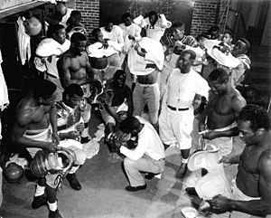 Coach Jake Gaither (standing, middle, white shirt) in the locker room with his Florida Agricultural and Mechanical University (FAMU) football team