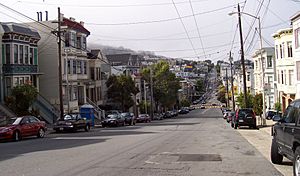 Eureka Valley, looking north on Castro Street from 20th. The giant rainbow flag at Castro and Market is just visible. In the summer months, fog tends to roll in over Twin Peaks and other hills to the west in the evenings and retreat again the next morning.