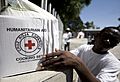 US Navy 100125-N-6266K-238 A Red Cross worker picks up a humanitarian box to give to an earthquake survivor in Port-au-Prince