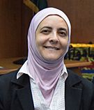 Rana Dajani smiling in a pink hijab in a meeting room.