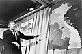 Robert McNamera pointing to a map of Vietnam at a press conference, 1965