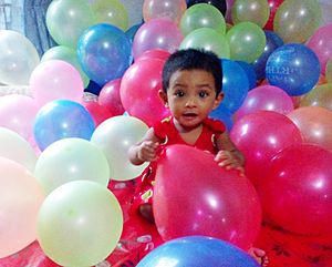 One year baby is playing with birthday balloons