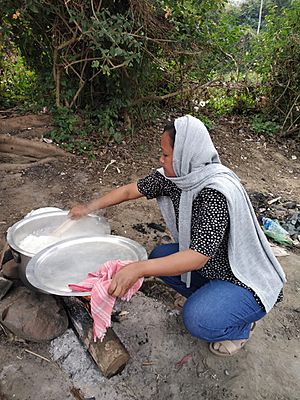 A woman in jeans and cooking in traditional way