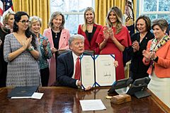 President Donald Trump holds up a newly signed House Joint Resolution 321