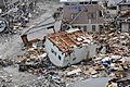 US Navy 110315-N-2653B-107 An upended house is among debris in Ofunato, Japan, following a 9.0 magnitude earthquake and subsequent tsunami