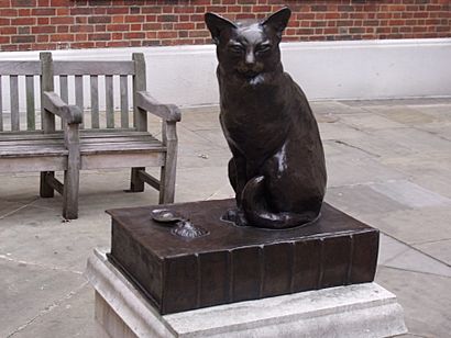 Bronze statue of a cat, sitting next to some oyster shells and on top of a dictionary which bears the inscription 'A Very Fine Cat Indeed'