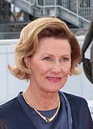 Crown Princess Sonja outdoors, dressed in dark blue, with a gold neckless.