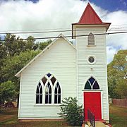 A white church with red doors and stained glass