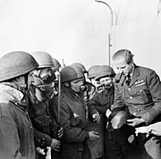 Wing Commander Percy Pickard, CO of No. 51 Squadron RAF, inspects a captured German helmet with troops from 2nd Parachute Battalion after the Bruneval raid, 28 February 1942. H17347