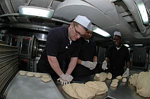 US Navy 071030-N-0167B-058 Culinary Specialist Seaman Brandon Freeman, of Lakeland, Fla., kneads dough into rolls in USS Kitty Hawk's bake shop