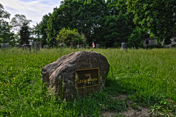 A rock with a metal plaque attached, reading "THE LEATHERMAN"