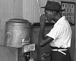 "Colored" drinking fountain from mid-20th century with african-american drinking (cropped)