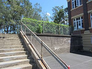 Retaining wall and stair between Depression-era Brick School Building (Block A) and tennis courts; from E (2015)