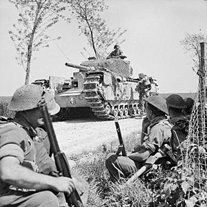 A Churchill tank halts near infantry of the 1st London Irish Rifles near Tanara during the advance to the River Po, Italy, 23 April 1945. NA24460