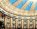 Interior of a domed atrium surrounded by hotel rooms and tall columns with light coming in through blue windows