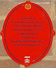 Oval red plaque bearing the words "In memory of District Officer Charles Pearson of the London Fire Brigade who died from injuries received at 100 Sidney Street near this site during the siege of Sidney Street on the 3rd of January 1911."