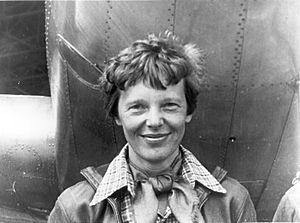 Amelia Earhart standing under nose of her Lockheed Model 10-E Electra, small