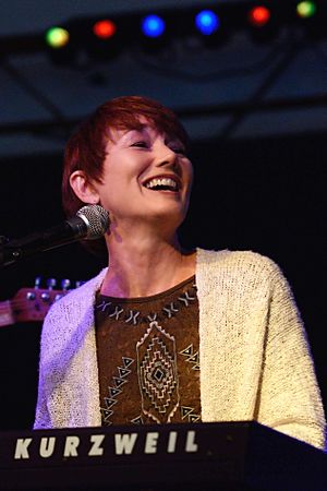 Lari White, singing into a microphone. Before her is a piano keyboard labeled "Kurzweil"