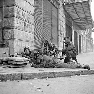 Paras from 5th (Scots) Parachute Battalion, 2nd Parachute Brigade, take cover on a street corner in Athens during operations against members of ELAS, 6 December 1944. NA20515