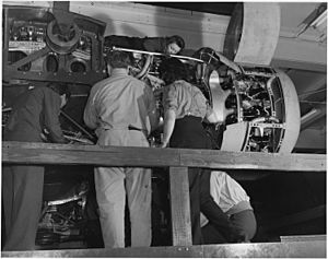 Installing one of the four engines of a new B-24E (Liberator) bomber on one of the assembly lines of ford's big... - NARA - 196388